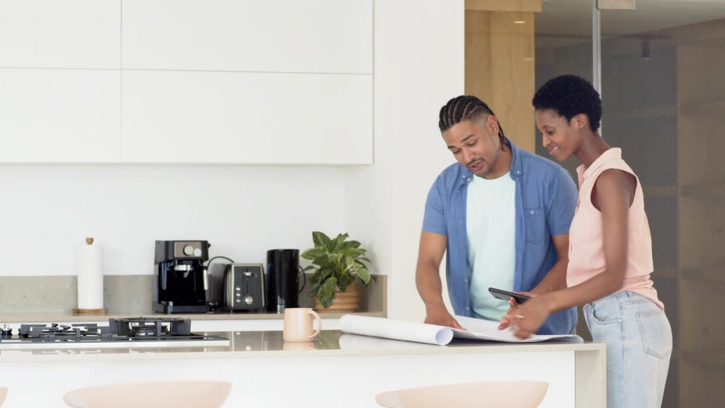 Maryland homeowners reviewing kitchen and bath remodel plans with blueprints and a tablet on a modern kitchen counter.