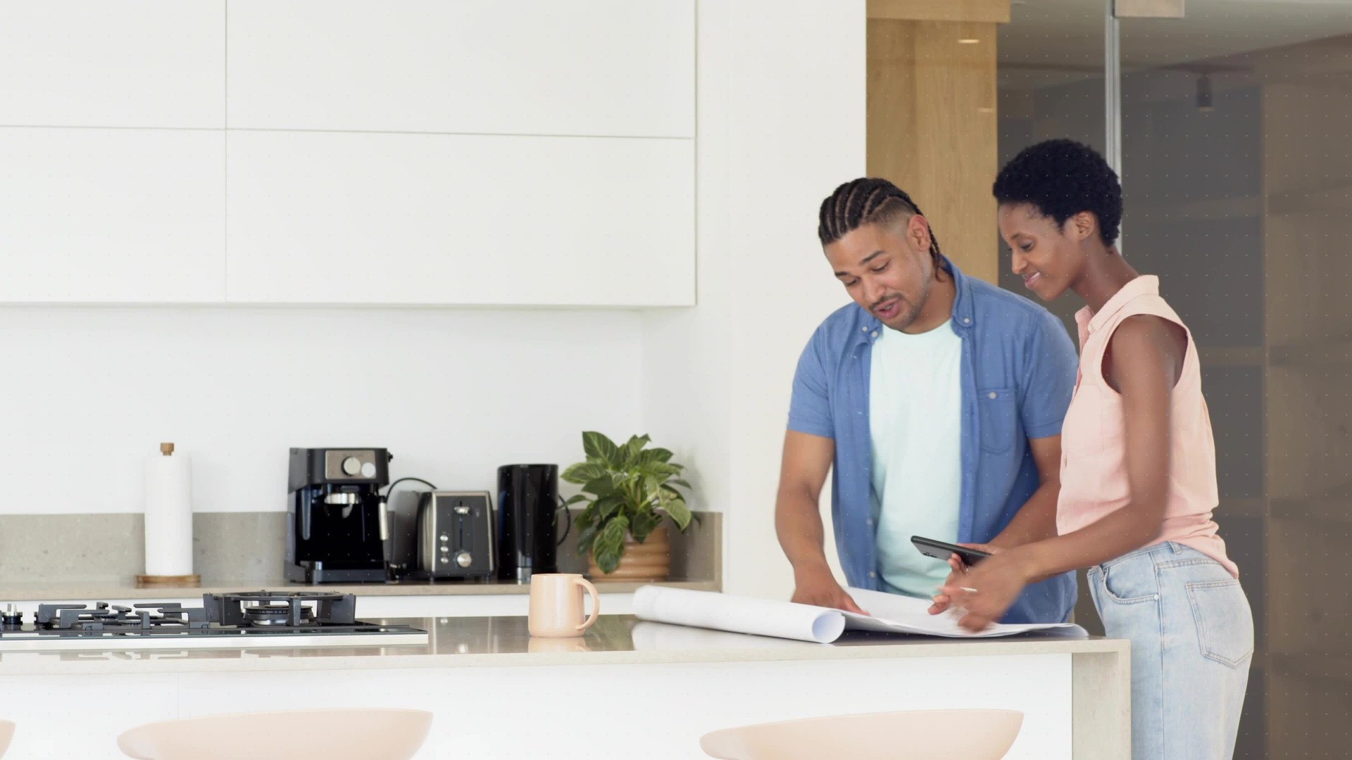 Maryland homeowners reviewing kitchen and bath remodel plans with blueprints and a tablet on a modern kitchen counter.