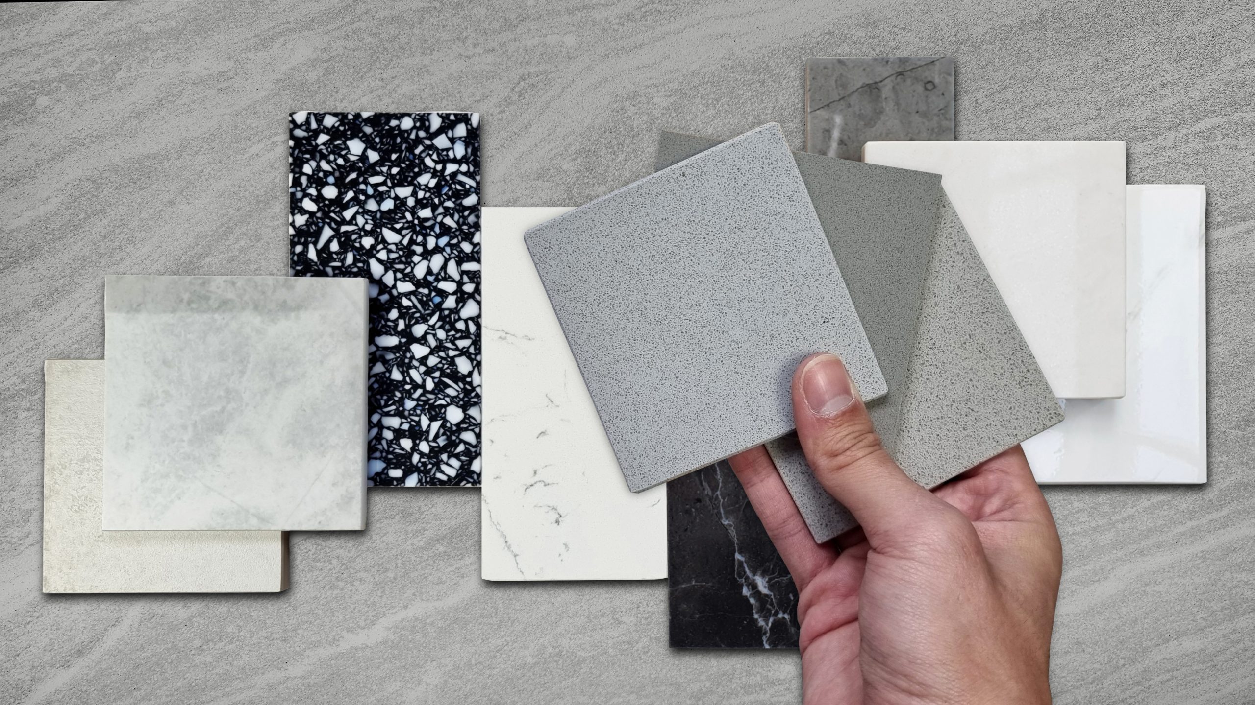 Designer hand placing engineered-quartz, marble, and solid-surface counter samples for a Maryland kitchen remodel material comparison.
